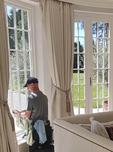 MJF Window Cleaning by a large window, cleaning or inspecting it in a bright room.